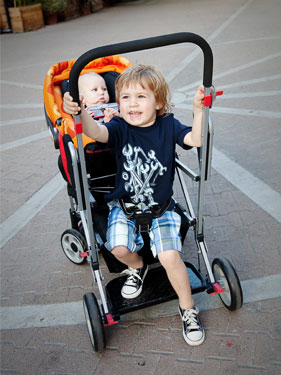 baby in stroller and kid standing