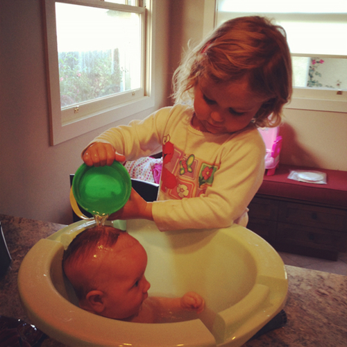Lucie giving Alice a bath in a newborn bath tub